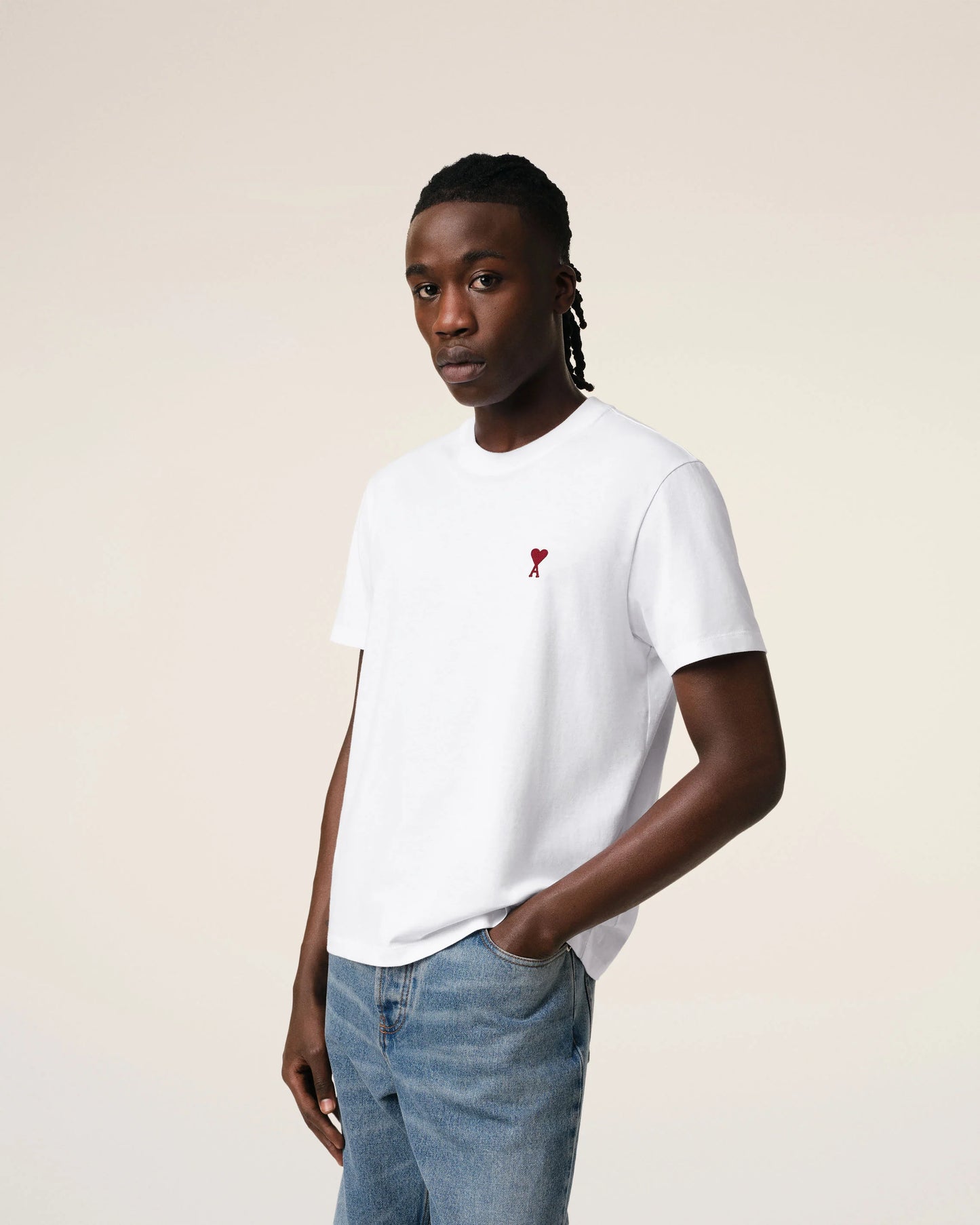 Person wearing a white t-shirt with a red logo on a plain background