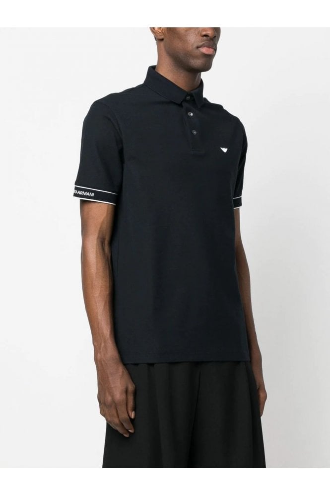 Person wearing a black polo shirt with white trim on a plain background