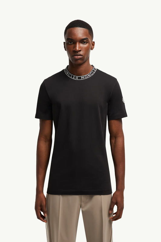 Man wearing a black t-shirt with a brand logo on a white background