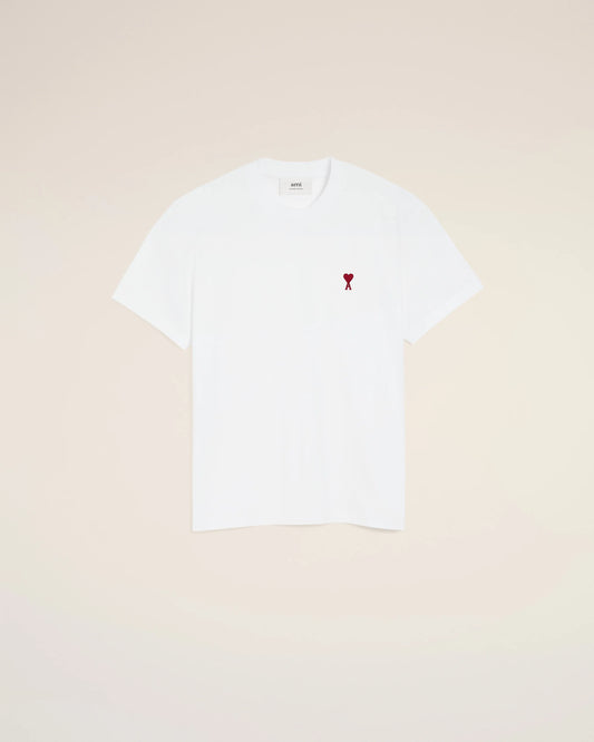 White t-shirt with a small red logo on a beige background