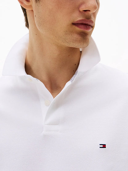 Close-up of a person wearing a white polo shirt with a small logo on a white background