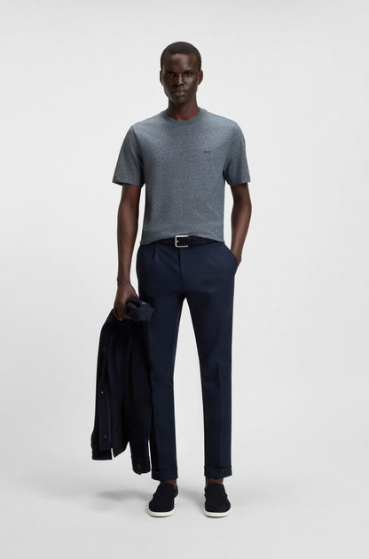 Man wearing a gray t-shirt and navy pants holding a black jacket on a white background