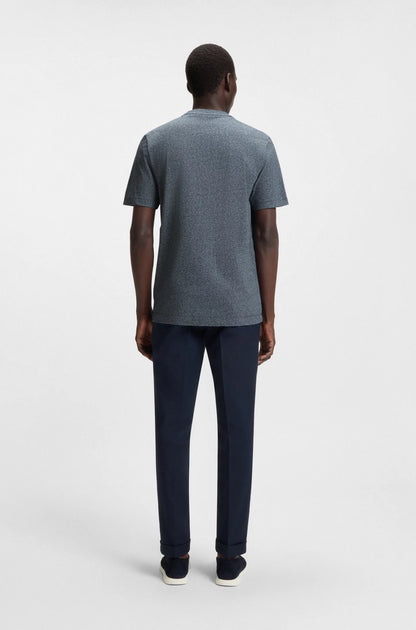 Man wearing a gray t-shirt and dark pants on a white background