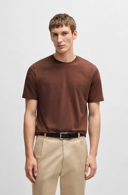 Man wearing a brown t-shirt and beige pants on a white background
