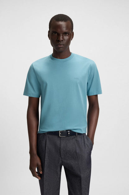 Man wearing a light blue t-shirt and dark gray pants on a white background