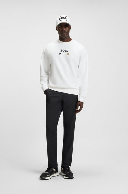 Person wearing a white sweatshirt with a logo, black pants, and a cap on a white background
