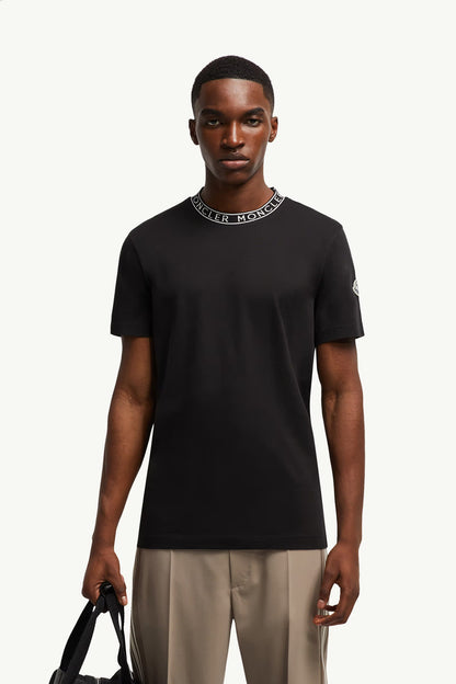 Man wearing a black t-shirt with a brand logo on a white background