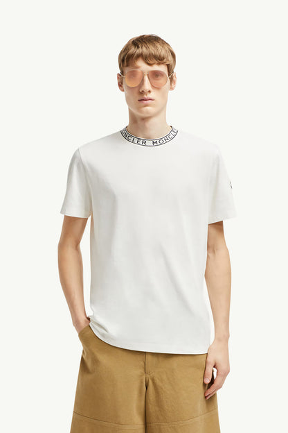 Man wearing a white t-shirt with a brand logo around his neck on a white background