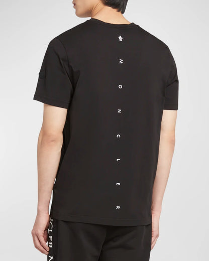 Person wearing a black t-shirt with 'Moncler' branding on the back against a white background