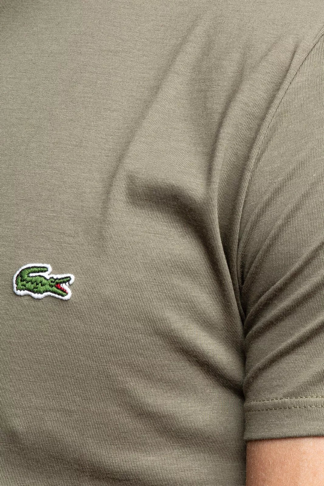 Close-up of a green t-shirt with a brand logo on a beige background